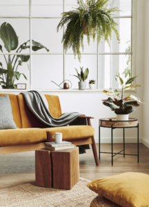 wooden sofa with a yellow linen and potted plants