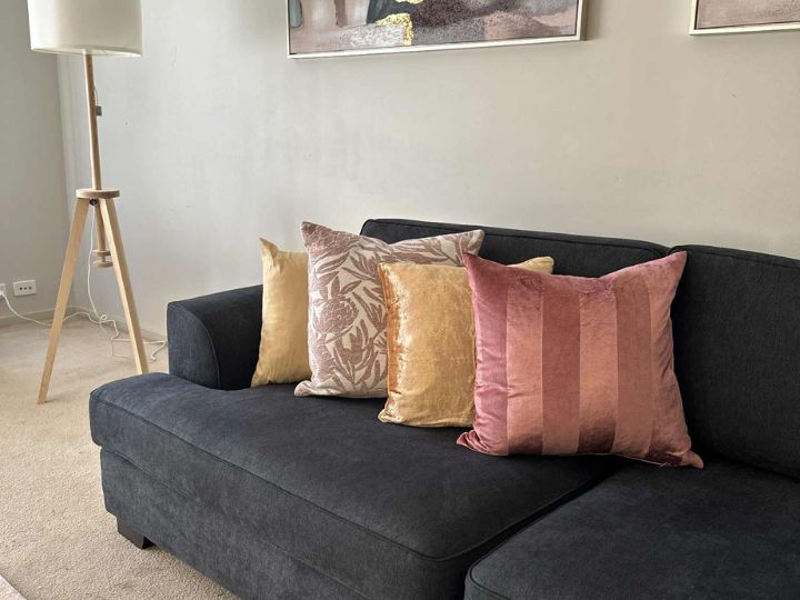 Cozy black couch with four pillows and a lamp, designed for an inviting home staging look.